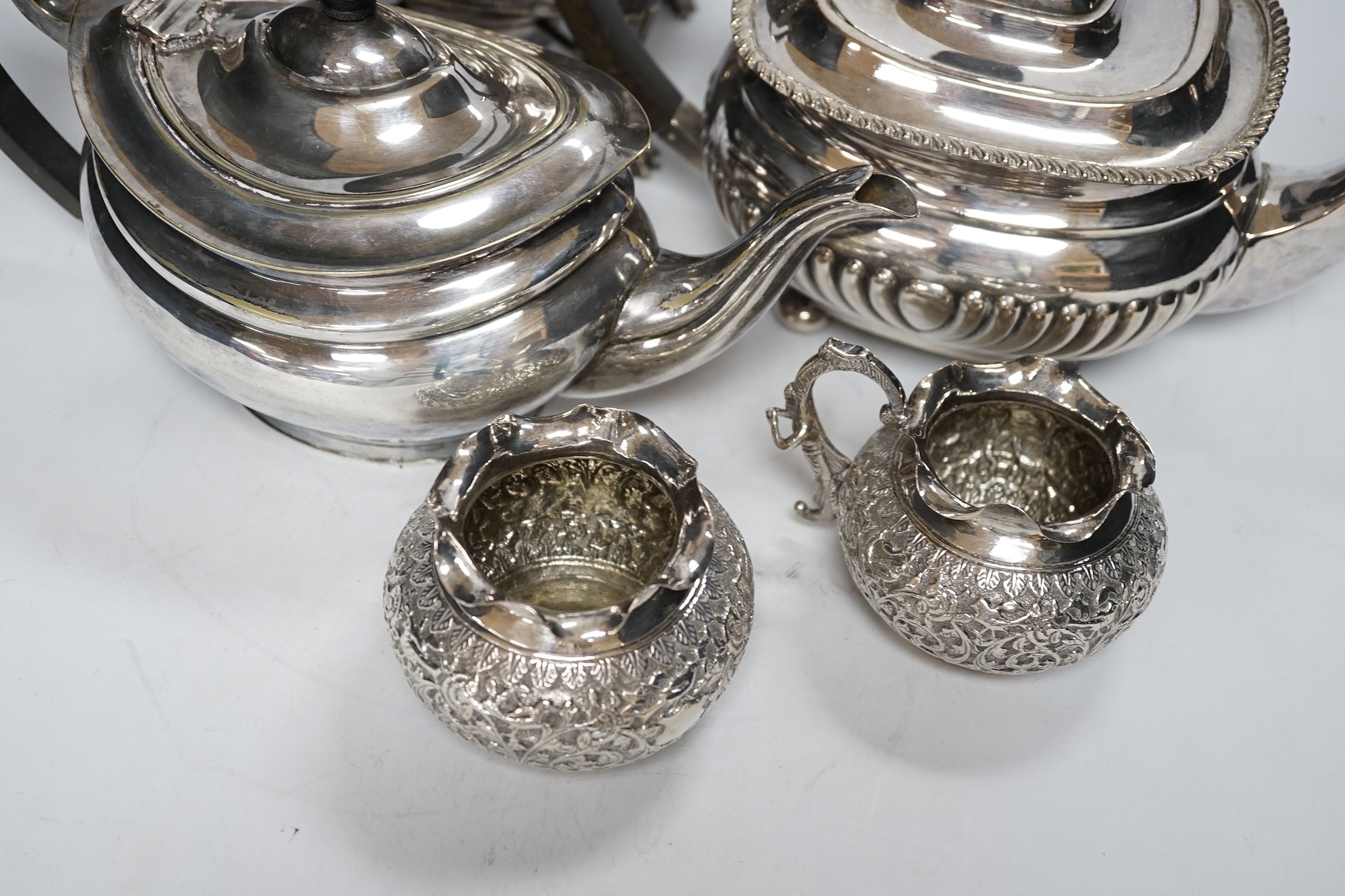 A plated kettle on stand, two plated teapots, a sugar bowl and a cream jug